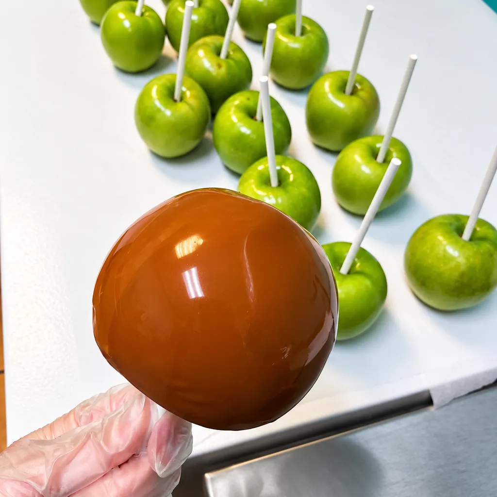 A glossy caramel apple on a stick